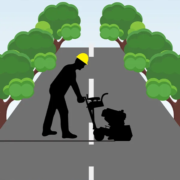 The worker uses a ground cutting machine to cut the pavement on the roadway.