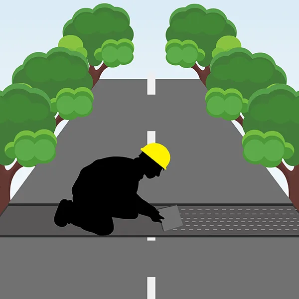 The worker levels asphalt with a trowel.