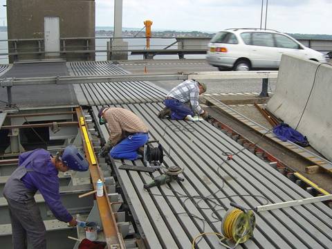 Three workers are setting the modular expansion joints in the large-span bridge.